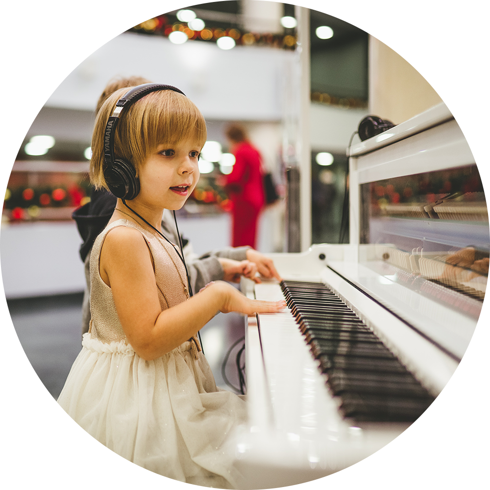 Child with headphones at a white piano